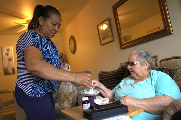 Lidia Vilorio, a home health aide, gives her patient Martina Negron her medicine and crackers for her tea on May 5th, 2021 in Haverstraw, New York.